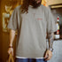 Man wearing a gray t-shirt with a logo in a casual setting